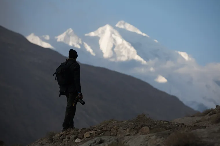 A photographer silhouetted against a snow peak in the Hunza Valley